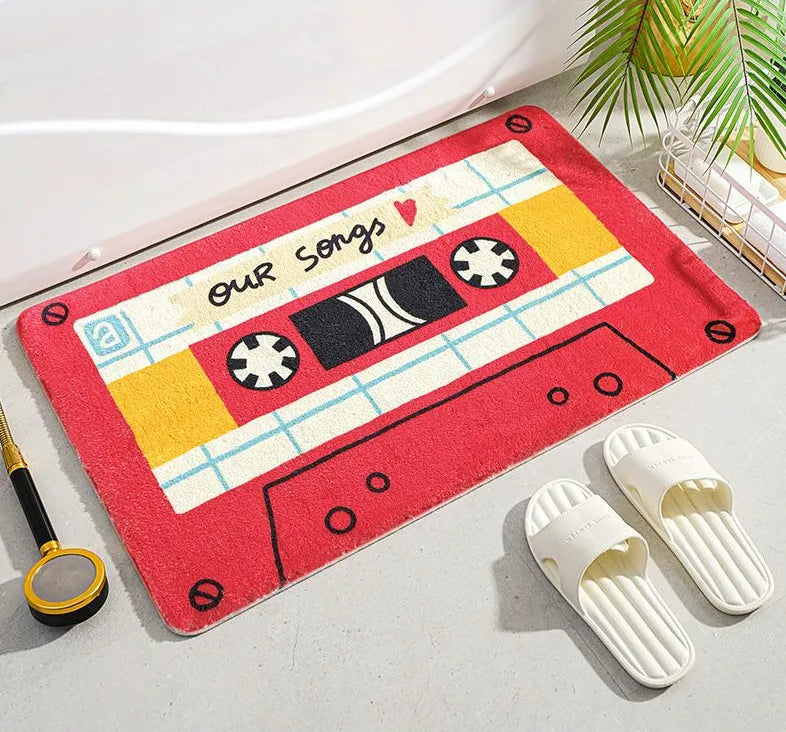 Tapis de bain en forme de cassette rouge, posé au sol près d’une baignoire blanche