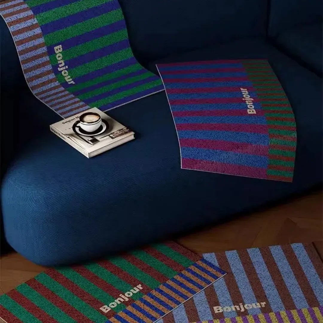 Trois tapis Bonjour aux motifs différents posés sur canapé et sol pour présentation coloris