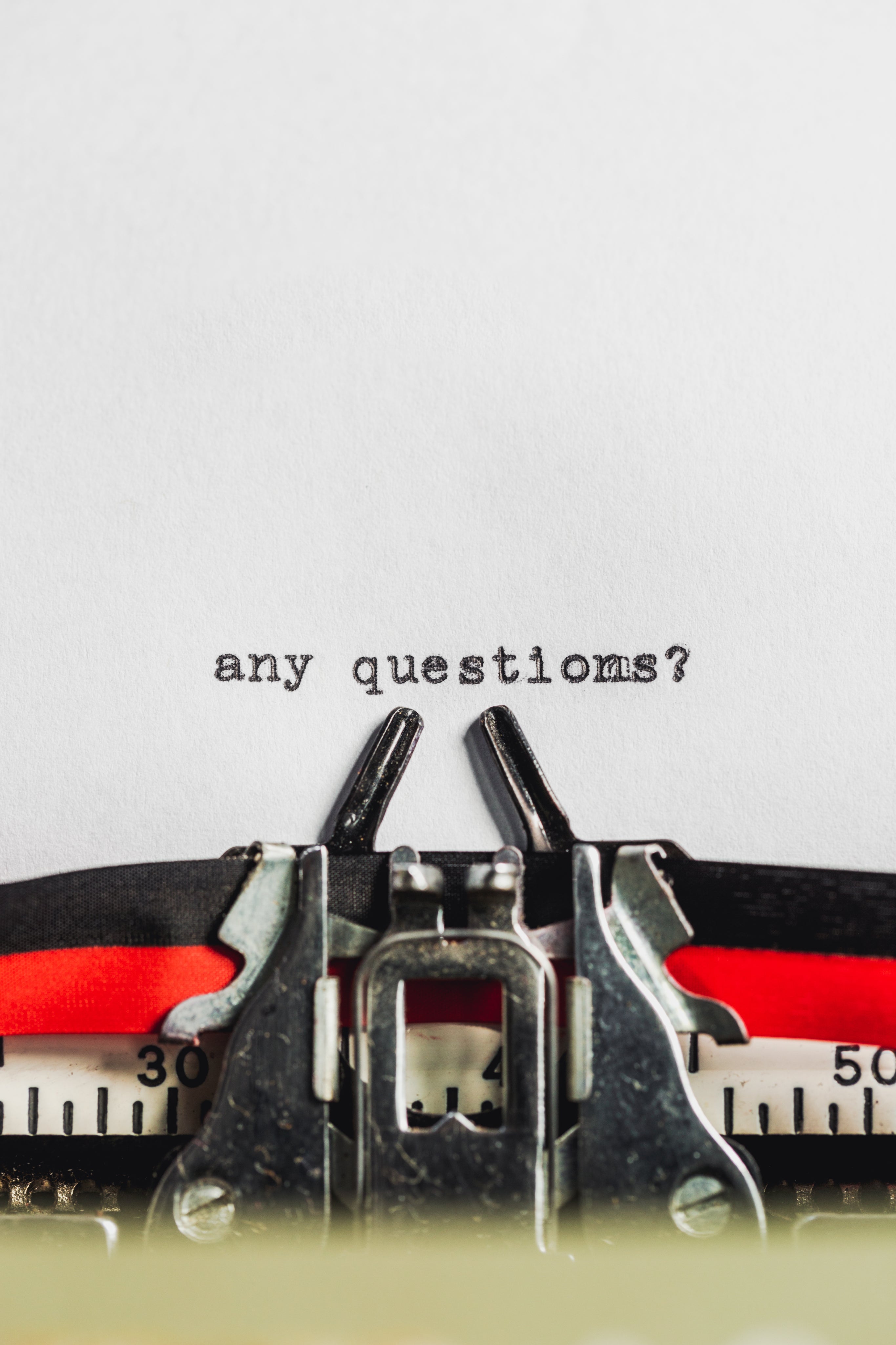 photo d'un papier dans une machine à écrire avec écris dessus "any questions?" pour inciter les gens à poser des questions ou à consulter la FAQ