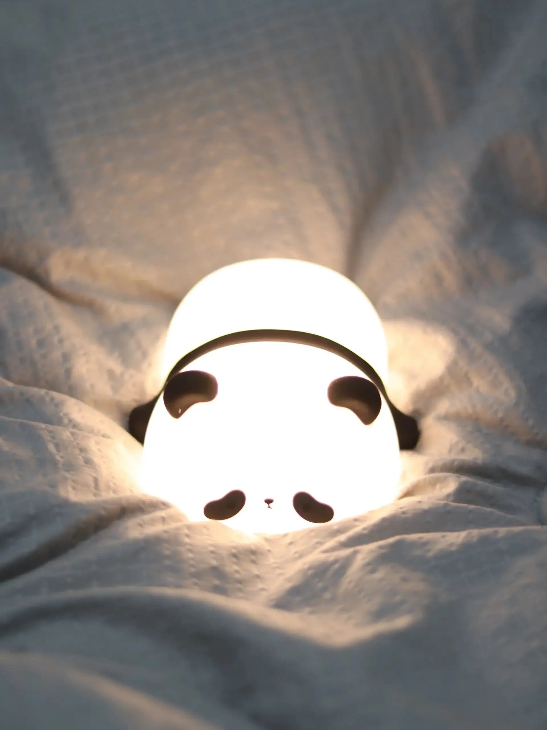 Veilleuse panda dans la pénombre d’un lit, lumière apaisante pour endormir les enfants