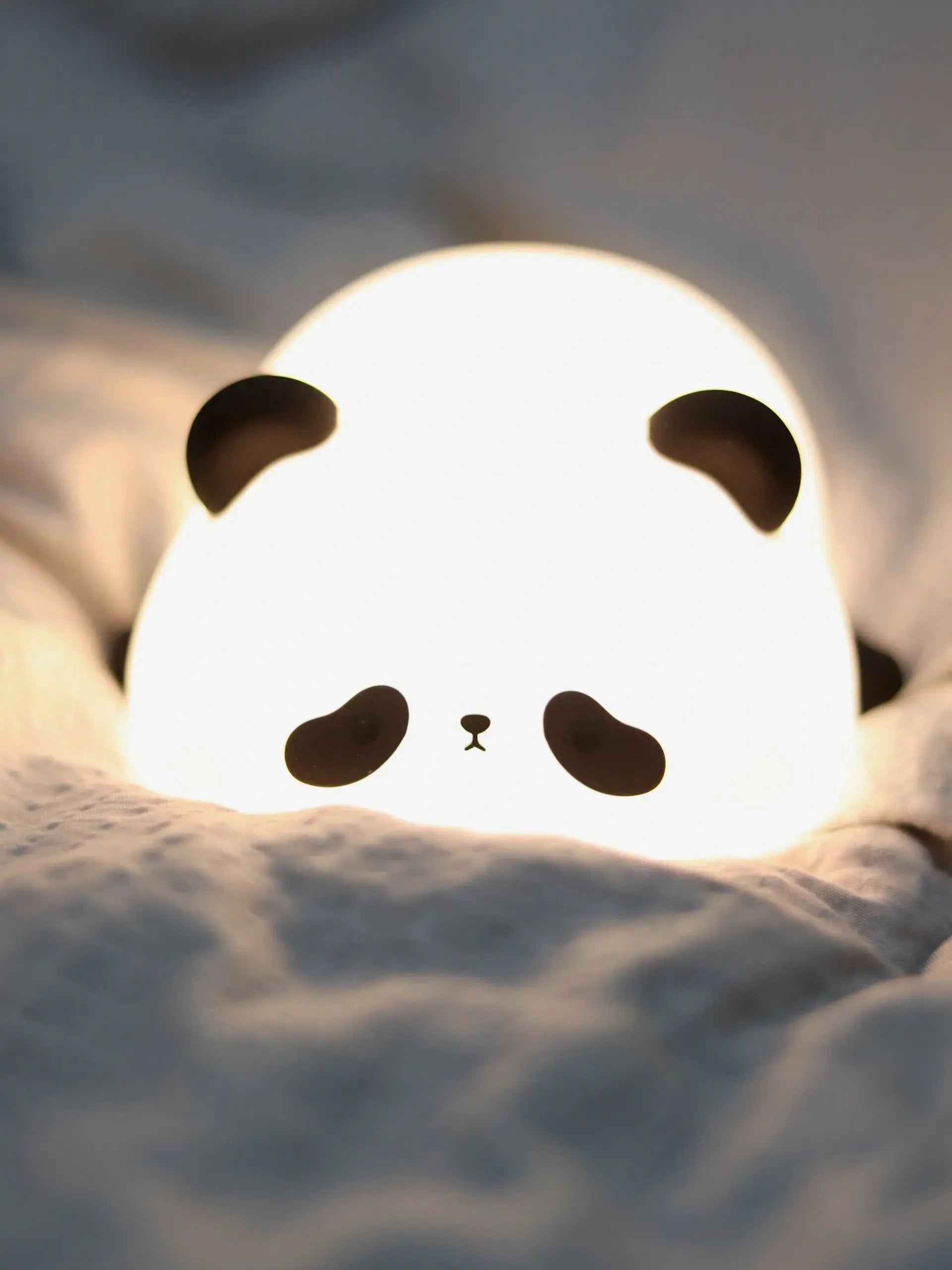 Veilleuse panda avec expression mignonne, posée dans un lit douillet